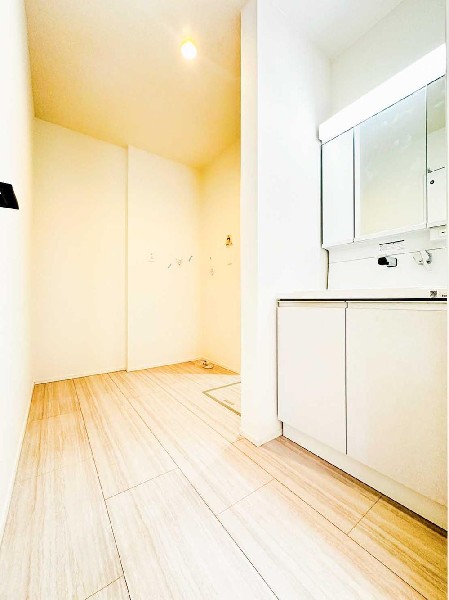 明るく清潔感のある洗面室。洗濯機置場にゆとりがあり、家族で使っても窮屈さを感じにくい設計です。