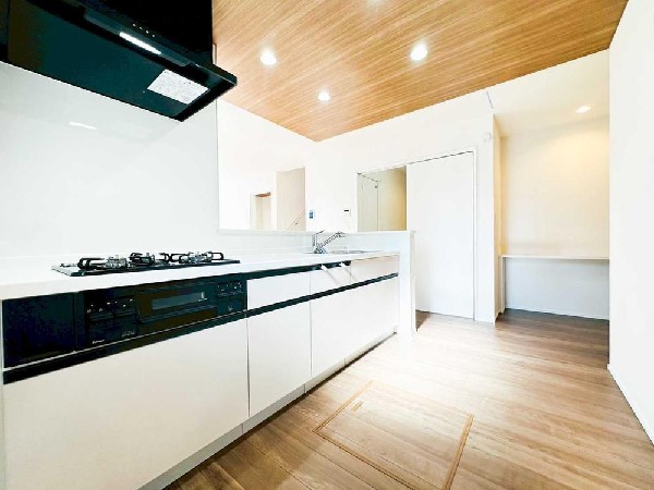 白基調のキッチンに木目天井が映える洗練LDK。広さと明るさを感じる空間で、毎日の料理や団らんが心地よく。