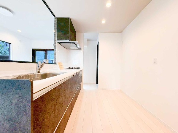 広々とした動線が魅力の対面キッチン。落ち着いたカラーの扉が上質な雰囲気を演出し、家事をしながら家族と会話を楽しめる明るい空間です。