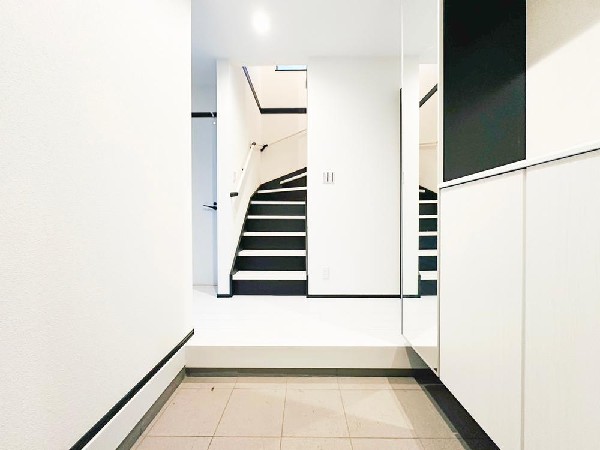 外観:玄関ホールはゆったりとした造りで、家族の出入りもスムーズ。大型ミラー付き収納で身支度も快適に。白×ブラックのコントラストが美しいスタイリッシュな空間です。