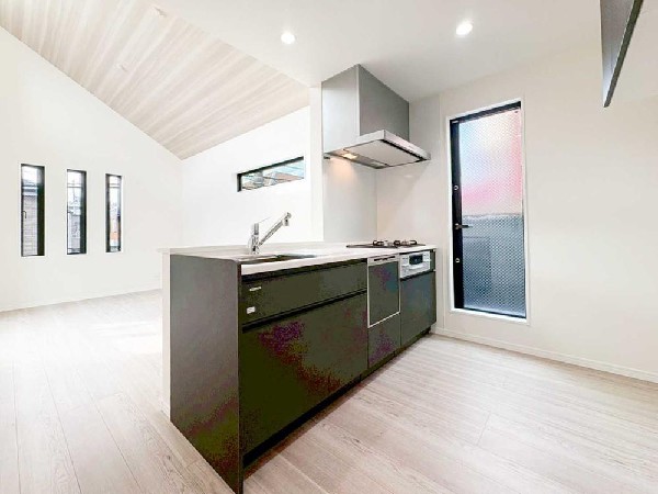 高窓と縦スリット窓からやわらかな光が差し込む、明るく美しいLDK。勾配天井と直線的なキッチンが空間に奥行きを生み、光とデザインが調和する上質な住空間です。