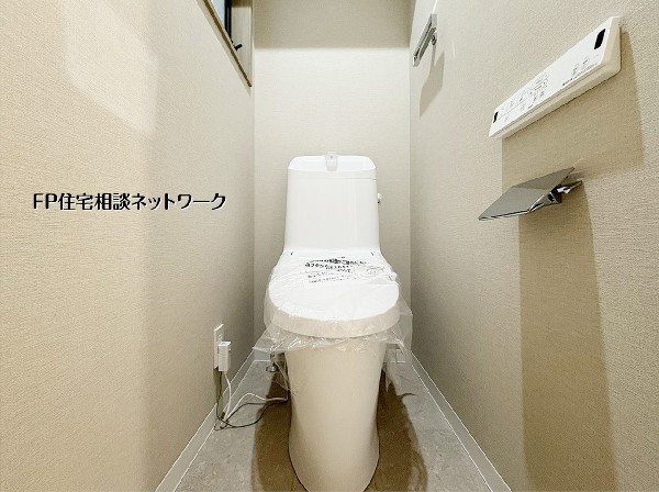 シンプルで美しいフォルムのトイレは、空間を広く見せるスッキリとしたデザイン。落ち着いたベージュのクロスが、清潔感の中に温かみをプラスします。