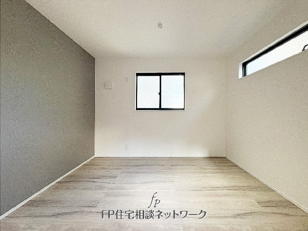 グレーのアクセントウォールが印象的な居室。2面採光で明るく、落ち着きのある空間です。