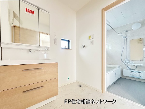 【洗面脱衣室】    明るい木目調が印象的な、清潔感あふれる洗面化粧台です。三面鏡の裏は収納になっており、小物もすっきり片付きます。バスルームと隣接した使い勝手の良い動線です。