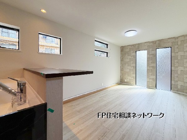 【LDK│21.37帖】  対面式キッチンから明るいリビングが見渡せる、開放感あふれる空間です。石目調のアクセントクロスが洗練された印象を与え、複数の窓から差し込む光が室内を優しく包み込みます。