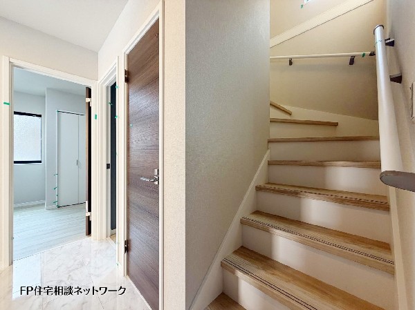 【玄関ホール│階段】  白を基調とした明るい廊下と階段スペース。大理石調の床が高級感を演出し、木目調のドアが温かみを添えます。手すり付きの階段や、各居室へのスムーズな動線が魅力的な住まいです。