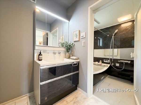 【洗面脱衣室】  清潔感あふれる洗面室は、三面鏡裏の収納や引き出しで小物もスッキリ片付きます。シックな石目調のデザインが高級感を演出。