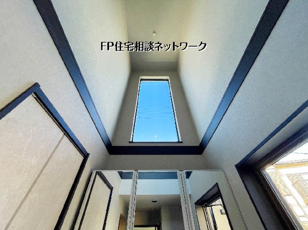 【玄関吹抜】  見上げれば青空。開放感あふれる吹抜け玄関が、ご家族を明るくお出迎えします。高窓からの陽光と鏡面収納が空間を広く演出し、毎日の「ただいま」が心地よい上質なエントランスです。