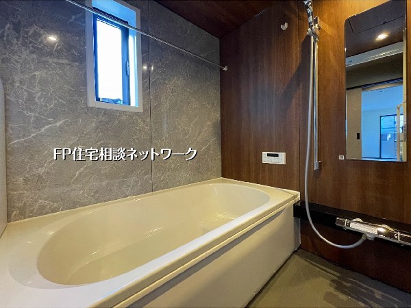 【浴室】  シックな木目調パネルと石目調の壁が織りなす、高級感あふれるバスルーム。一日の疲れを癒すリラックス空間です。ゆったりとしたバスタブに浸かり、至福のバスタイムをお楽しみください。