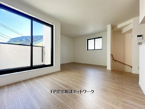 大きな窓からたっぷりと光が差し込む明るい空間。木目の床が温かみを演出し、家具の配置がしやすい開放的な間取り。家族が自然と集まる心地よいリビングです。