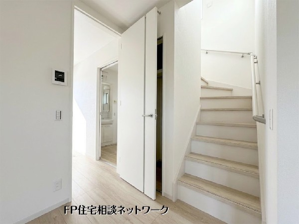 【リビングイン階段】  白を基調とした清潔感あふれる内装です。階段横には便利な収納スペースを完備。廊下の先には洗面室があり、家事動線にも配慮された間取りが魅力です。