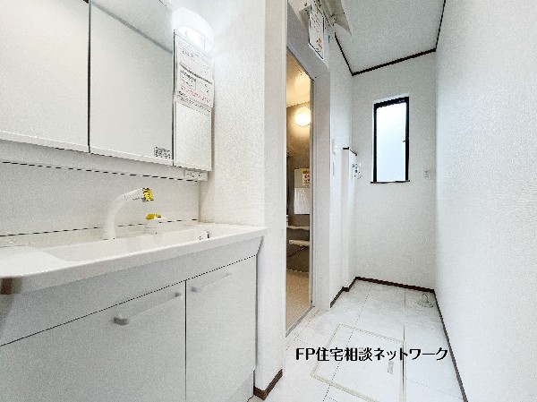 【洗面室】  白を基調とした清潔感溢れる洗面脱衣室。三面鏡タイプの洗面化粧台は、鏡裏に小物をスッキリ収納でき、忙しい朝の身支度をスムーズにサポートします。