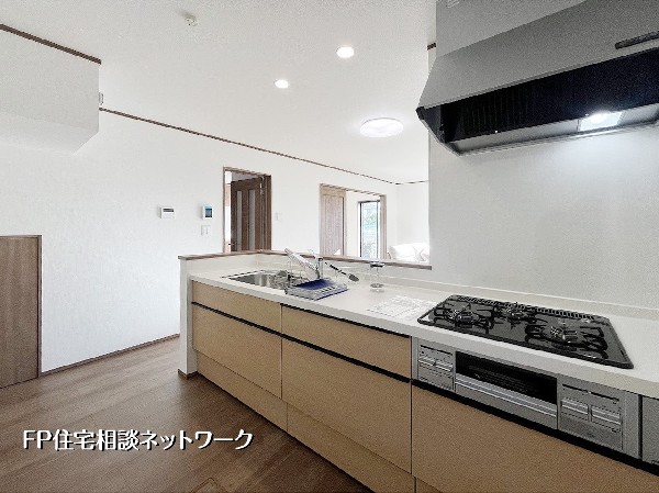 【カウンターキッチン】  料理中もリビングでくつろぐ家族との会話が弾む、開放的な対面式キッチン。明るく清潔感のある空間に、ぬくもりを感じる木目調のデザインが調和します。