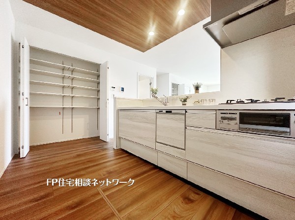 美しいキッチンと収納力が両立！ 大容量のパントリーが生活感を隠し、いつでもすっきりとした空間を保ちます。木目調の温かみと明るさが魅力の、理想的な調理スペースです。