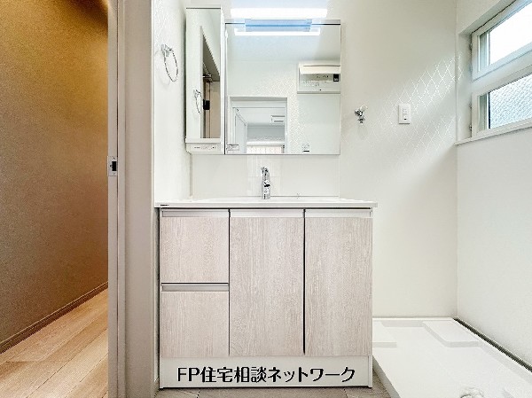 清潔感あふれる洗面化粧台は、三面鏡収納付きで身支度もスムーズ。窓があり自然光が入るため明るく、洗濯機置場もゆとりある配置で家事動線に配慮した洗面空間です。