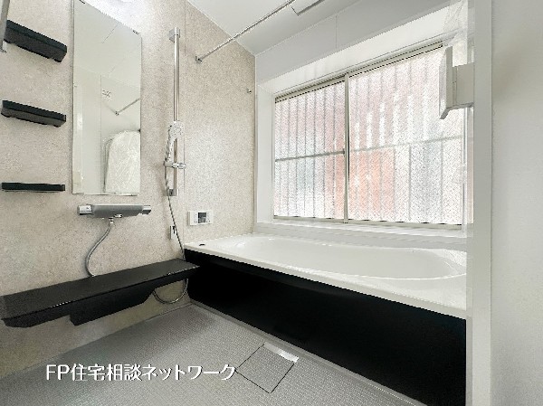 大きな窓付きで換気性能に優れた、清潔感あふれるバスルーム。自然光が差し込む明るい空間は、湿気がこもりにくくお掃除もスムーズです。黒の収納棚が空間を引き締めるモダンなデザインで、快適なバスタイムを。