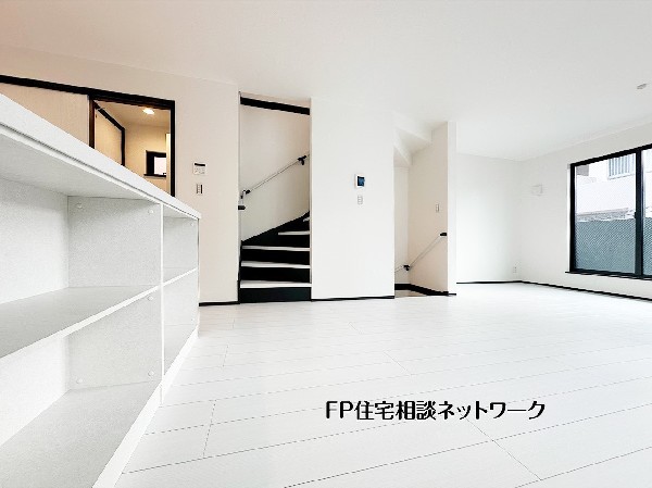 【キッチンカウンター収納】白を基調とした内装に黒の階段がアクセントのモダンな住空間。2階リビング設計により、プライバシーを保ちつつ明るい陽光が差し込みます。