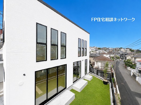 外観:【外観│庭】  青空に映える白を基調としたスタイリッシュな外観。規則正しく並んだ黒枠の窓と大きな開口部がアクセントとなり、モダンな雰囲気を演出しています。